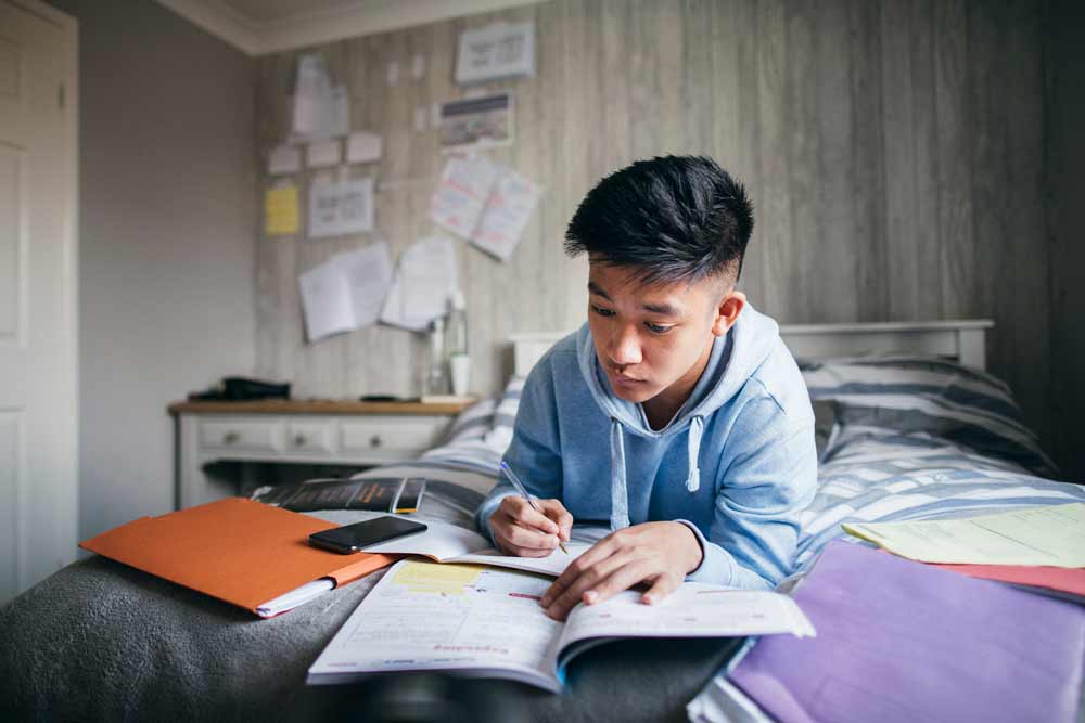 Student doing homework on bed