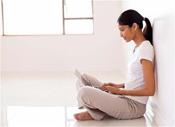 Woman sitting on floor uses laptop at home