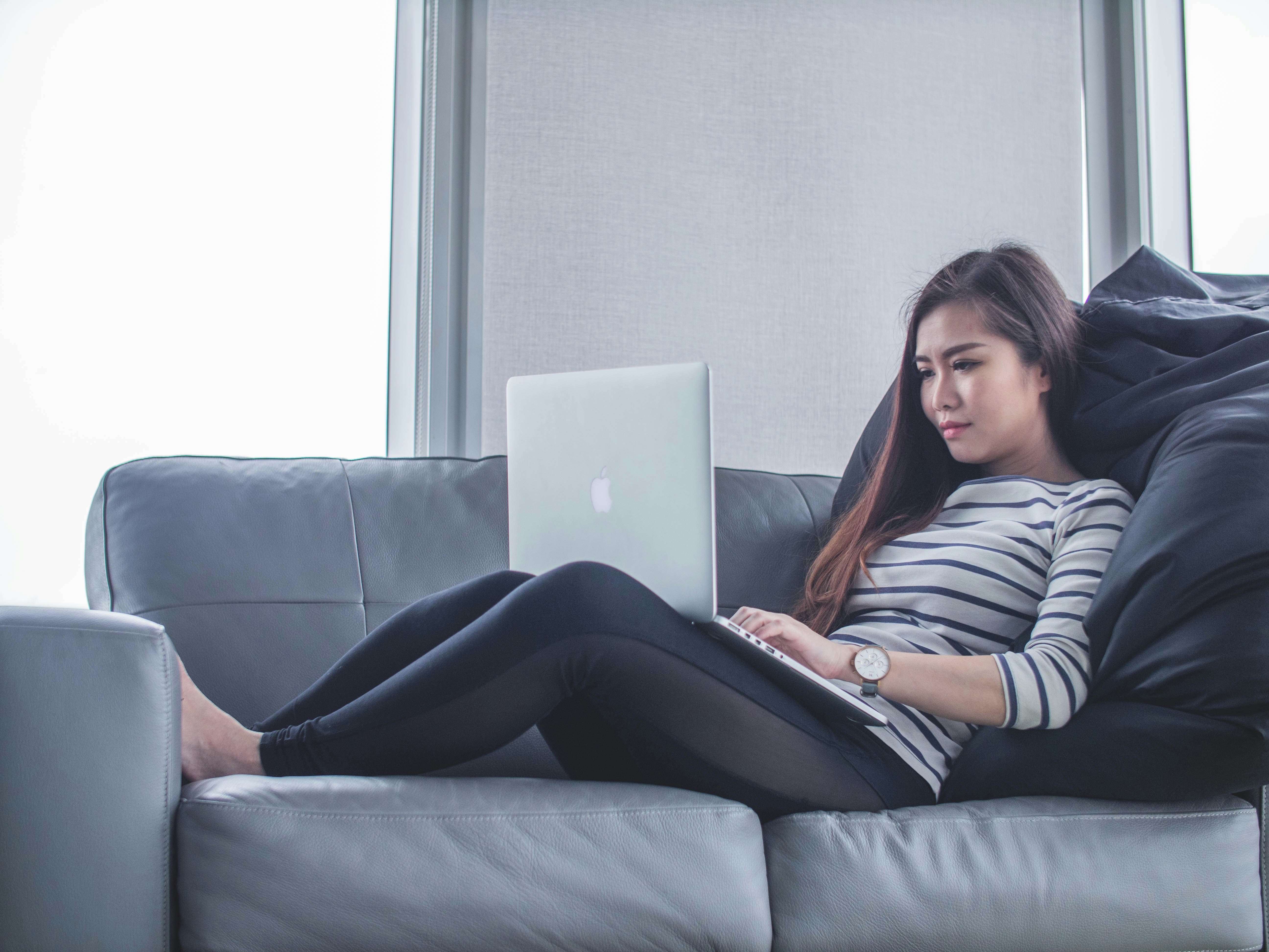 Woman sitting on a couch using a macbook pro
