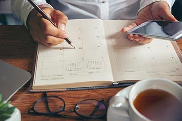 hands checking calendar at desk with mobile