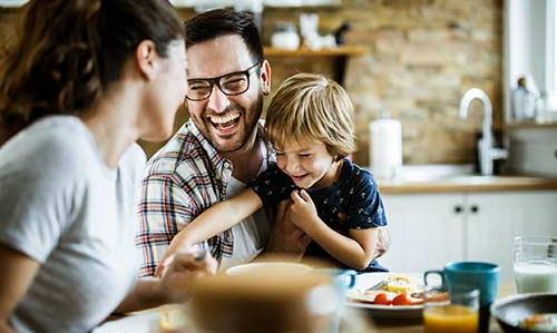 young family laughing at kitchen table